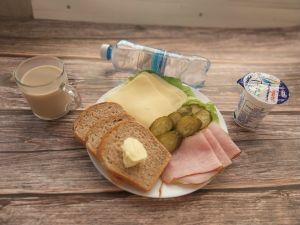 Zdjęcie przedstawia Dietę z ogr.łatwoprzsw. węglowodanów: Masło extra Szynka krucha z pieca wieprzowa, parzona Ogórek konserwowy Kawa zbożowa z mlekiem Chleb Graham Jogurt naturalny  Woda mineralna Sałata zielona  Ser mozzarella 